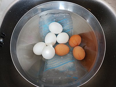 Gekochte Eier und Kühlpackung in einer großen Schale Wasser