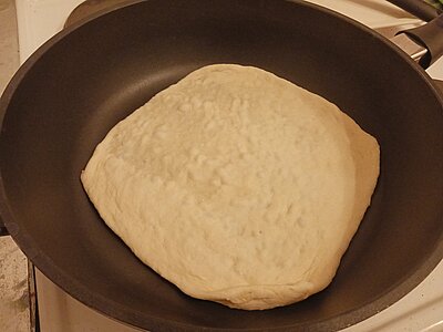 Ein Teigfladen in einer beschichteten Pfanne