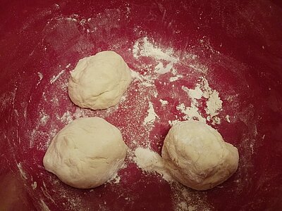 Drei runde, mehlbestäubte Teigbällchen in einer Rührschüssel