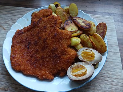 Gebratene Kartoffeln, paniertes Schnitzel, ein mariniertes Ei